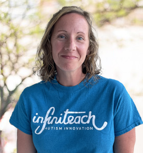 White woman with curly, light-brown hair and a friendly, closed-lip smile wearing a bright blue InfiniTeach t-shirt.